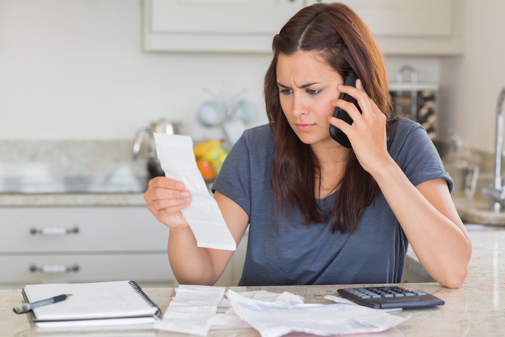 Woman calling while calculating bills in kitchen