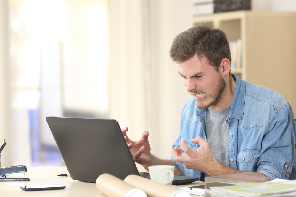 Entrepreneur angry and furious with a laptop in a little office or home