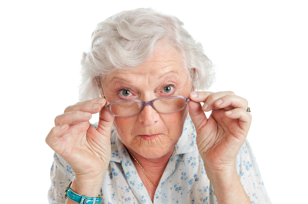 Happy surprised old senior lady looking through her eyeglasses isolated on white background