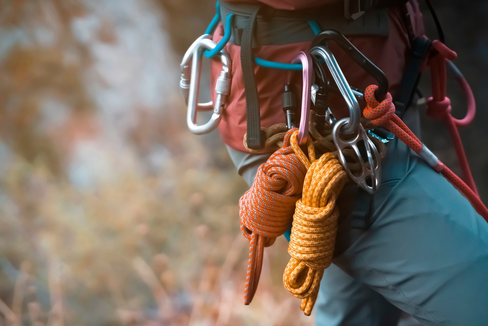 Climbing equipment, ropes, carabiners, harness, belay, close-up of a rock-climber put on by a girl, the traveler leads an active lifestyle and is engaged in mountaineering.