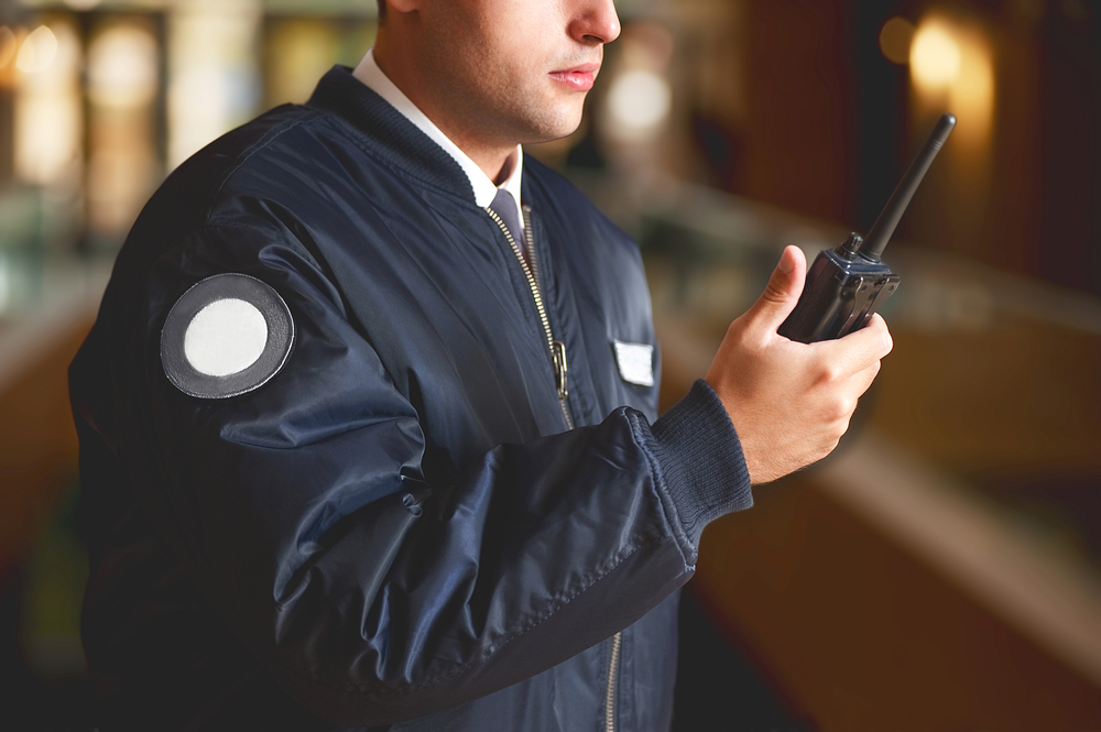  a cut face close up in a security guard with a portable wireless transceiver on a blurry background